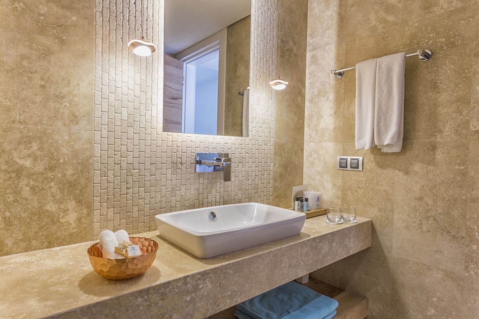 A bathroom with a large rectangular sink, a mirror, and a towel rack.