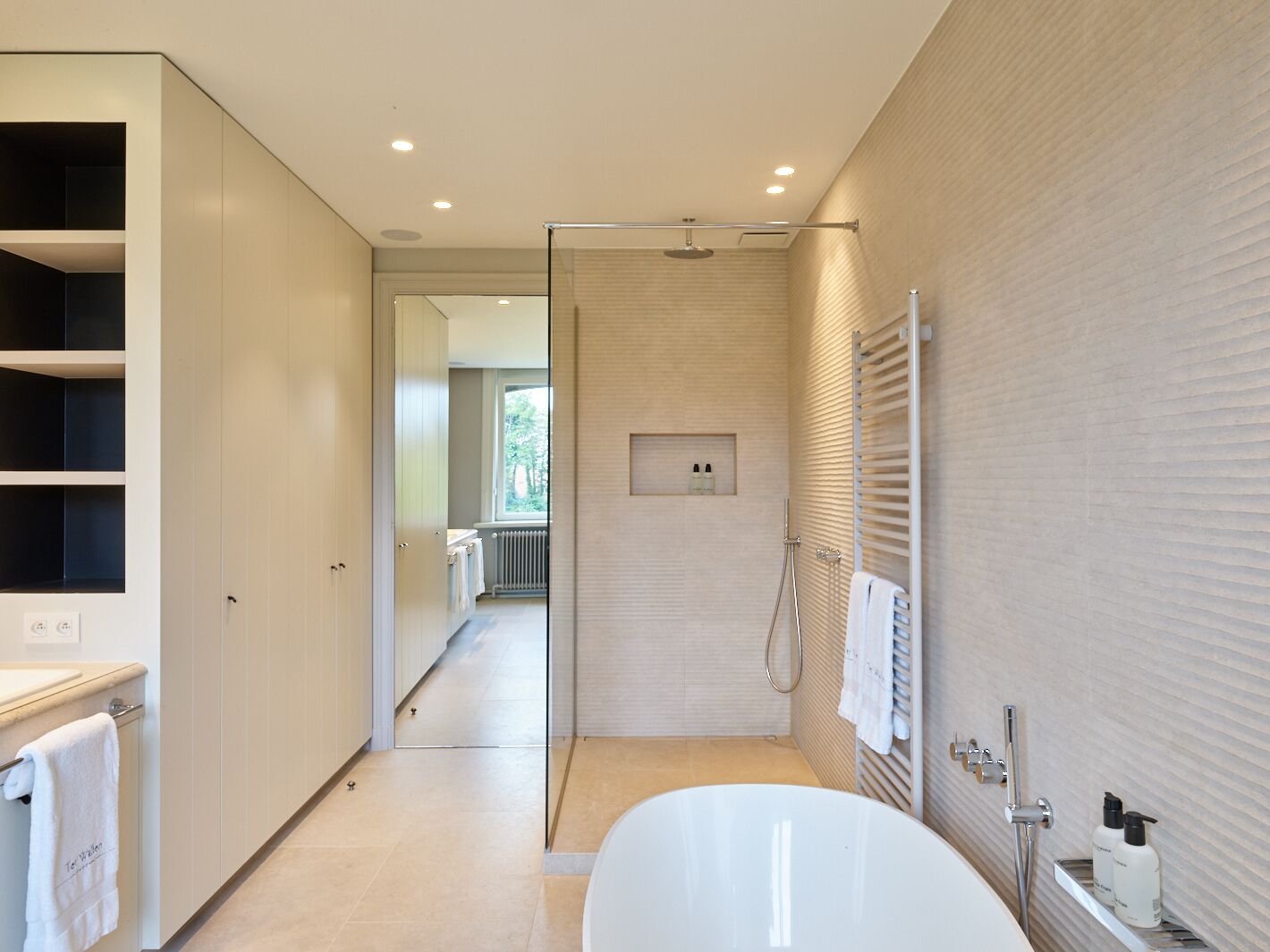 A modern bathroom with a walk-in shower, a bathtub, and a vanity with a towel rack.