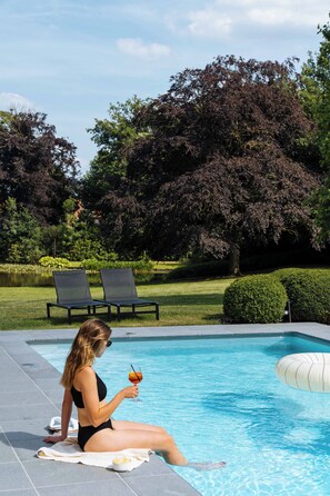 Piscine extérieure en saison, parasols, chaises longues