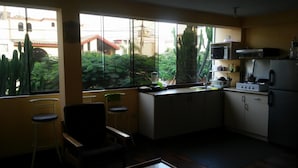 Uma cozinha compacta com vista para um jardim, incluindo micro-ondas, fogão e comodidades básicas.