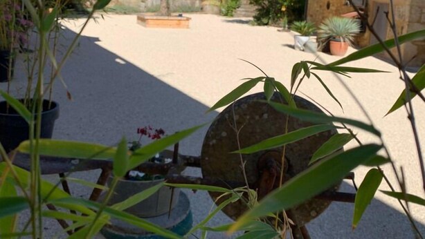 A courtyard with stone buildings, a wheelbarrow, and potted plants. - 50 Route du Gourdon (Cénac-et-Saint-Julien)