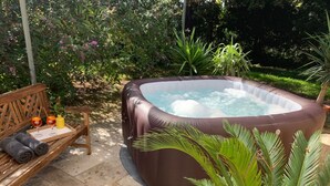 A hot tub in a garden with a wooden bench and towels. - 50 Route du Gourdon (Cénac-et-Saint-Julien)