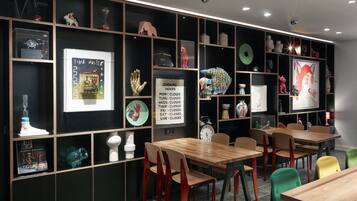 Un interior moderno con mesas y sillas de madera, objetos decorativos en estantes y un reloj de pared.