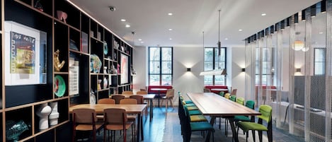 Un comedor moderno con una mesa de madera larga, varias sillas y una estantería con diversos objetos.