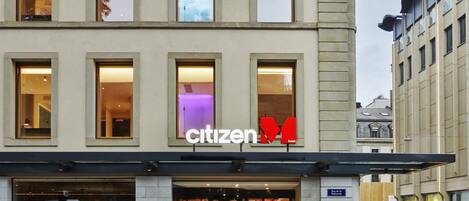 Un hotel con fachada moderna, amplias ventanas y un llamativo letrero que dice 'Citizen Hotel'.