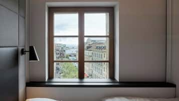 A bedroom with a large window, a bed, and a bedside lamp.