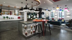 Un interior moderno con una isla central, taburetes de bar e iluminación colgante.
