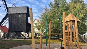Un parque infantil con estructuras de madera para escalar y una red de cuerdas.