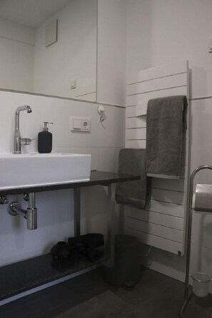 A modern bathroom with a white sink, black soap dispenser, and a towel rack with a towel. - Pension Fahnermuehle (Gierstädt)