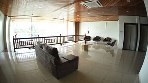 A spacious lobby with a wooden ceiling, a sofa, two armchairs, a small table, and a view through a glass partition. - Swamy Hotel (Cruzeiro do Sul)