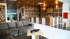 A modern hotel lobby with a wooden ceiling, a reception desk, a sofa, and a coffee table. - Swamy Hotel (Cruzeiro do Sul)