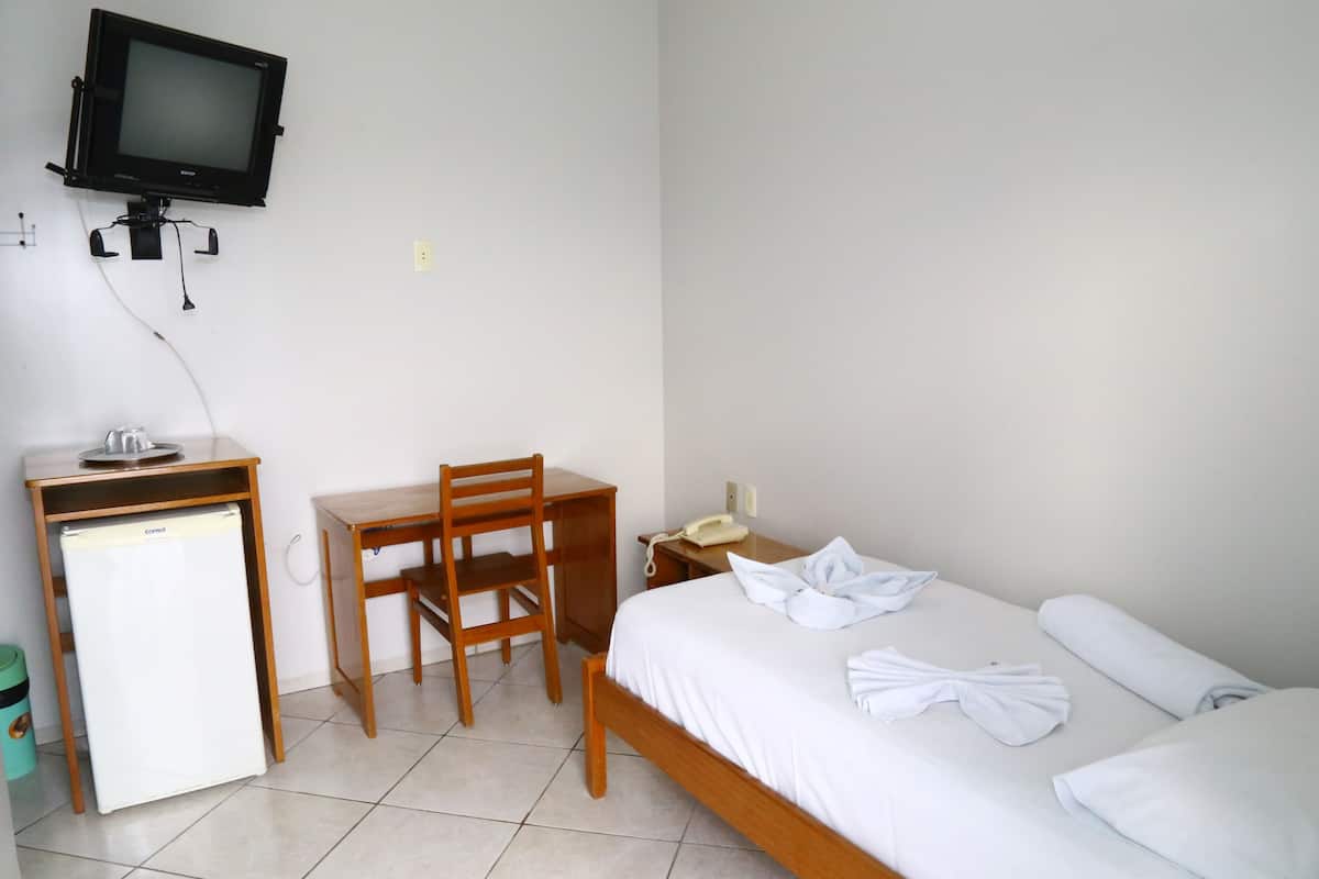 Une chambre d’hôtel équipée d’un lit, d’un bureau, d’une chaise, d’une télévision et d’un réfrigérateur.