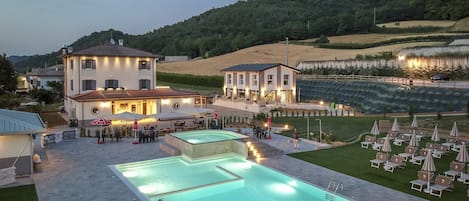 A hotel with a swimming pool, outdoor seating, and a view of the surrounding hills.