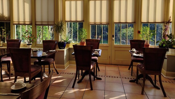 A conservatory with a high ceiling, large windows, and a central door. - The Arundel Park Hotel (Arundel)