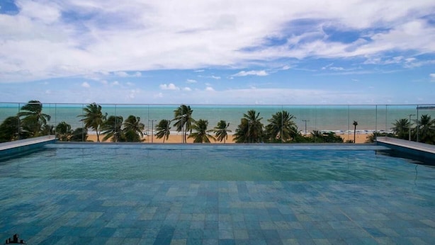 A swimming pool with a view of a beach and palm trees. - Infinity at the Sea by Welkom (João Pessoa)
