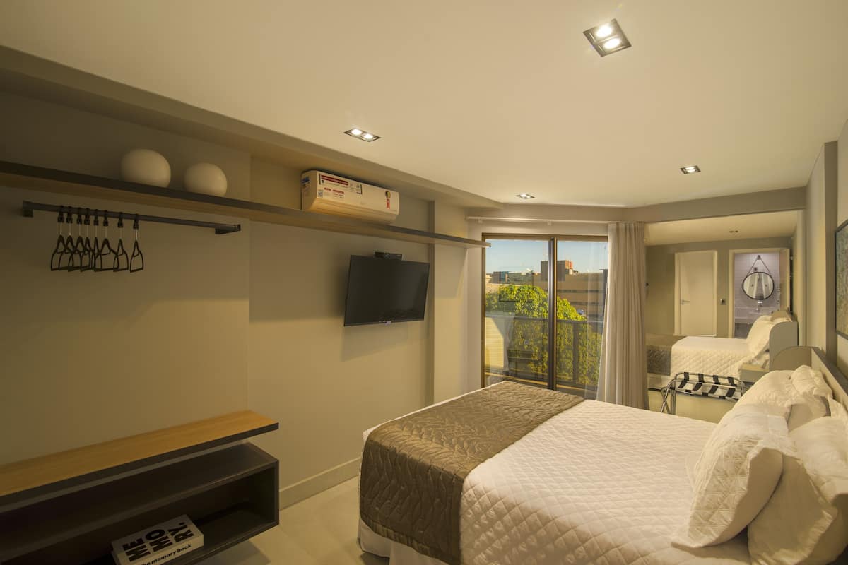 Ein modernes Hotelzimmer mit Bett, Fernseher, Balkon und Blick auf die Stadt.