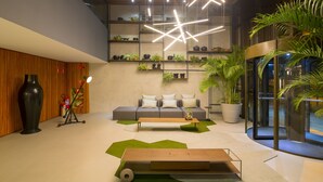 A modern lobby with a sofa, coffee table, and potted plants. - Infinity at the Sea by Welkom (João Pessoa)