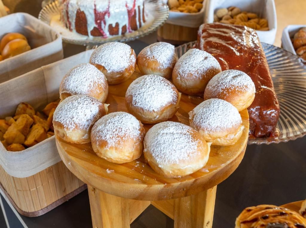 Une table où sont présentés divers pâtisseries, notamment des petits pains saupoudrés de sucre glace.