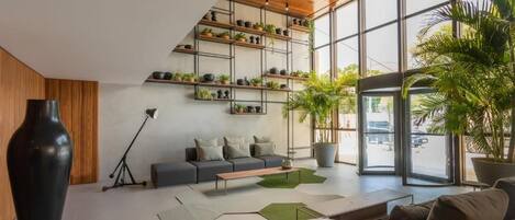 Um interior moderno com teto de madeira, sofá cinzento, mesa de centro e um vaso preto grande.