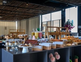 A buffet with various food items and desserts, a wooden structure, and a large window in the background.