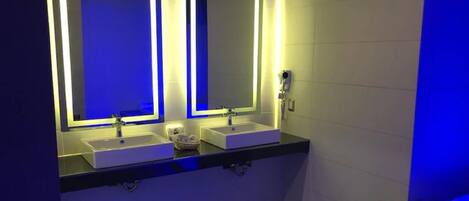 Une salle de bain moderne avec deux vasques, chacune dotée d’un miroir et d’un éclairage sous le meuble.