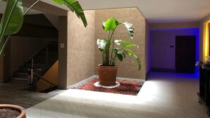 A potted plant in a corner with a tiled floor and a staircase in the background. - Hotel Plaza Arteaga (Monterrey)