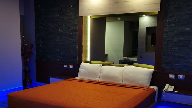 A modern bedroom with a large bed, a bedside table, a mirror, and a nightstand. - Hotel Plaza Arteaga (Monterrey)