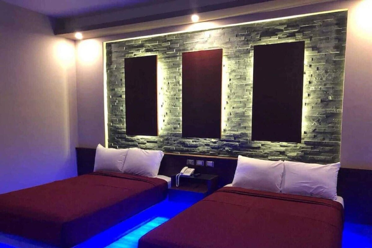 A room with two beds, a stone wall, and a small table with a phone.