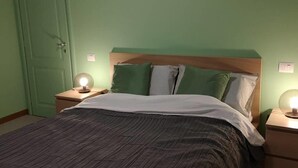 A bedroom with a bed, two bedside tables, and a door. - Two-room apartment overlooking the Basilica (Loreto)