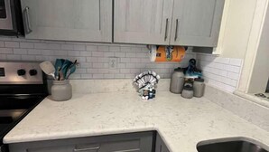 A kitchen with grey cabinets, a white countertop, and a stainless steel sink. - Location! Location! Townhouse.    STR Permit #: 040846 (Hilton Head)
