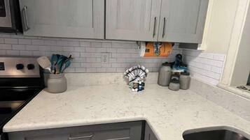 Una cocina con gabinetes grises, una encimera blanca y un fregadero de acero inoxidable.