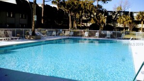 A rectangular swimming pool with a shallow end, surrounded by a white fence and lounge chairs. - Location! Location! Townhouse.    STR Permit #: 040846 (Hilton Head)