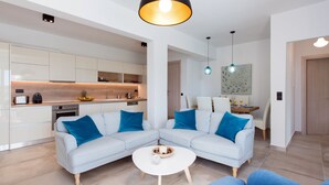 Ein modernes Wohnzimmer mit einer Sofagarnitur, einem Couchtisch und einer Küchenzeile im Hintergrund.