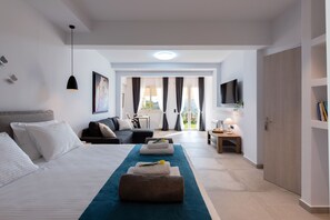 A modern hotel room with a bed, a sofa, a desk, and a TV. - Ionian Sun - Holiday Home with Sea View (Corfu)