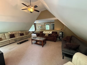 A living room with a ceiling fan, two sofas, a coffee table, and a bookshelf.