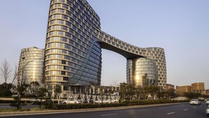 A modern hotel with a distinctive curved structure and a large overhang. - Novotel Zhengzhou Airport (Zhengzhou)