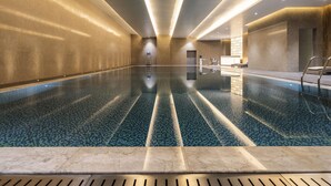 A large indoor swimming pool with a tiled floor and a central ladder. - Novotel Zhengzhou Airport (Zhengzhou)