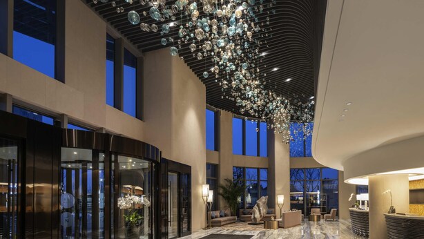 A spacious lobby with a marble floor, a reception desk, and a large glass entrance. - Novotel Zhengzhou Airport (Zhengzhou)