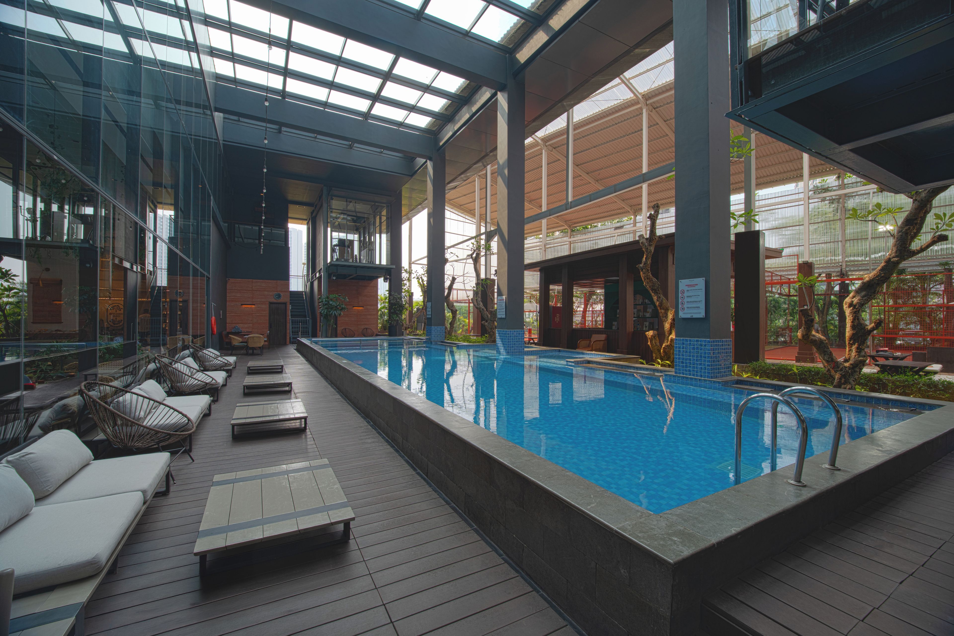An indoor swimming pool with lounge chairs and a glass ceiling.