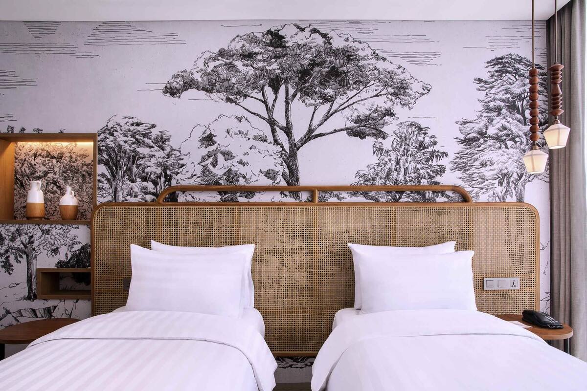 Ein Hotelzimmer mit einem großen Bett, einem Nachttisch, einer Lampe und einem Wandbild.
