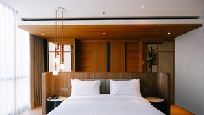 Ein modernes Hotelzimmer mit einem großen Bett, einem Holz-Kopfteil, Nachttischen und einer Pendelleuchte.