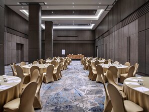 Una sala conferenze con tavoli rotondi, sedie beige e una moquette fantasia.