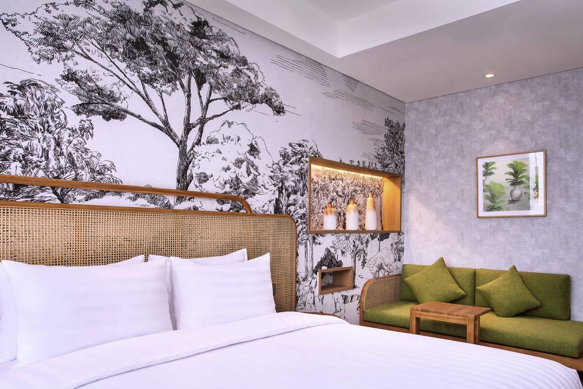 Une chambre à coucher avec un grand lit, un canapé vert, une petite table et une étagère murale agrémentée d’objets décoratifs.