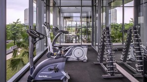Ein modernes Fitnessstudio mit Cardiogeräten, Hanteln und Blick auf eine Stadtkulisse durch große Fenster.