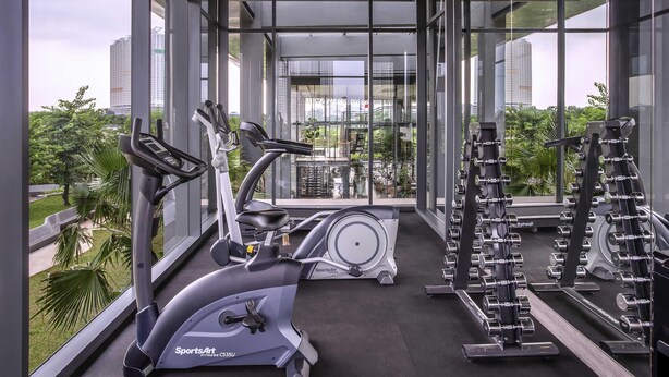 Ein Fitnessstudio mit Cardiogeräten, Kraftmaschinen und Blick auf eine Skyline durch große Fenster.