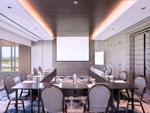 Conference room with a long table and chairs, featuring a large projection screen for presentations and meetings.
