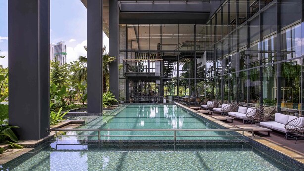 Ein moderner, überdachter Pool mit klarem Wasser, umgeben von Liegestühlen und Glaswänden.