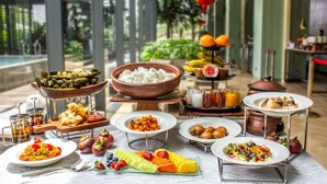 Ein reichhaltiges Buffet mit verschiedenen Speisen, darunter Obst, Gemüse und eine Auswahl an asiatischen Gerichten.