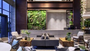 Eine moderne Lobby mit Sitzgelegenheiten, einer großen Wand mit Pflanzen und einem Empfangstresen.