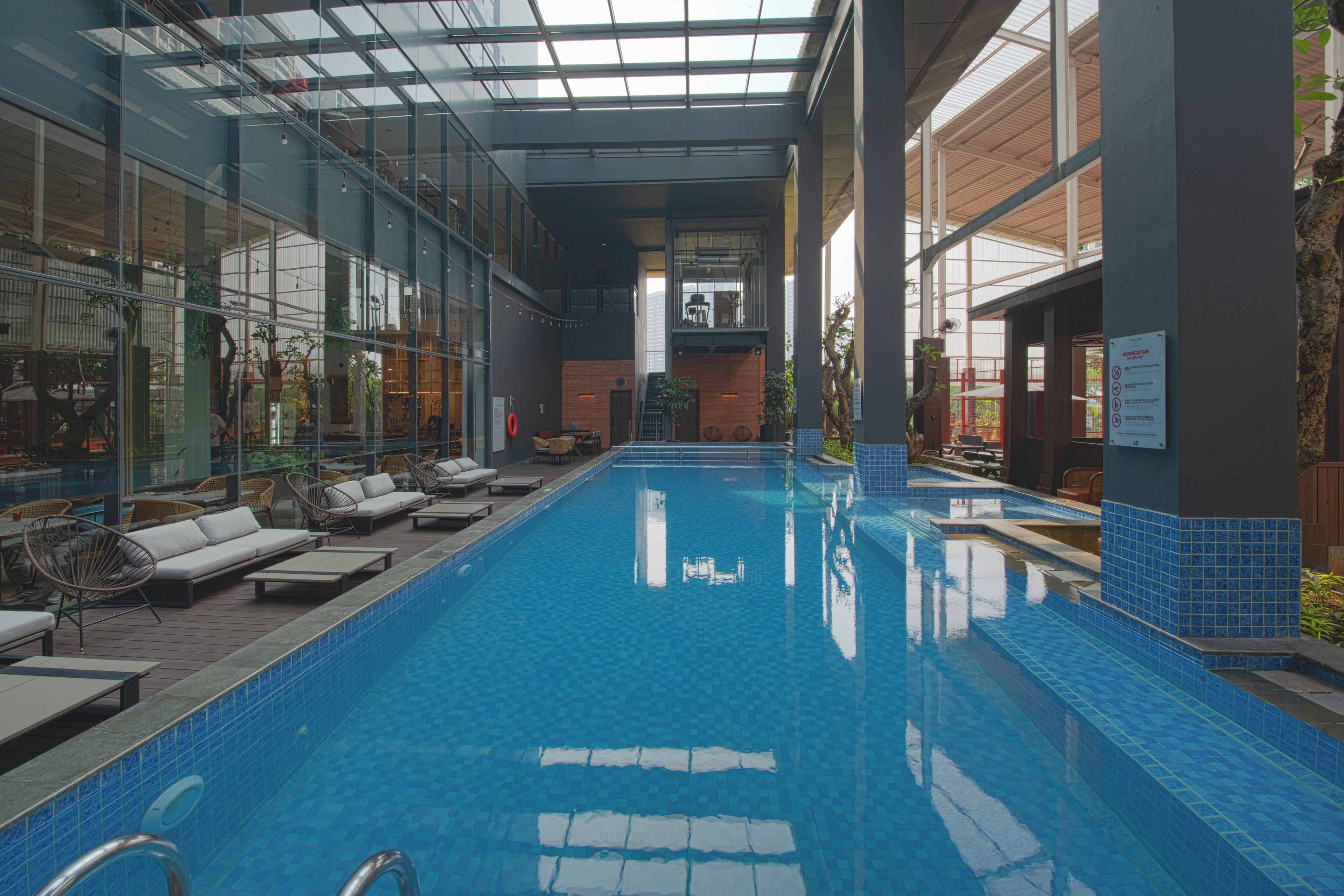Una piscina interior con sillas de descanso y techo de vidrio.